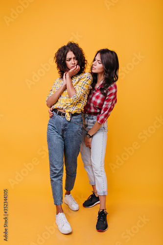 in yellow blouse is upset and her best friend comforts her. Girls with curls discuss sad story © Look!