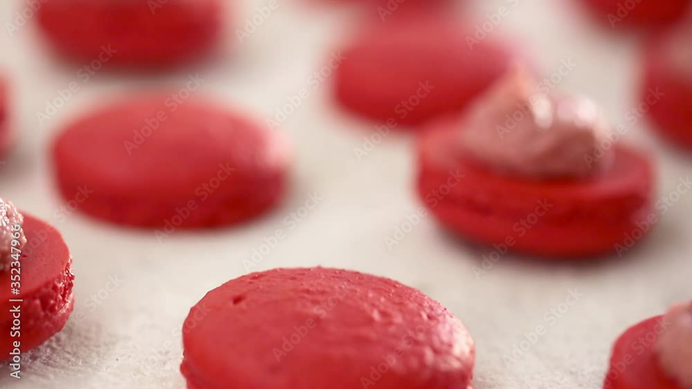Close-up view of many rows of red opened halves with filling macarons macaroon on white background. Classical French dessert. Close-up view of many rows of red opened halves with filling macarons macaroon on white background. Classical French dessert.
