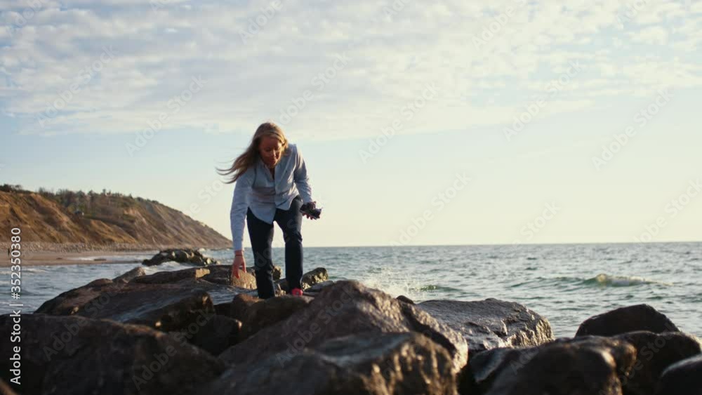 Photographer Clambering Over Rocks By Sea Photographer Clambering Over Rocks By Sea