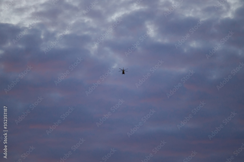 one helicopter fly in the pink clouds