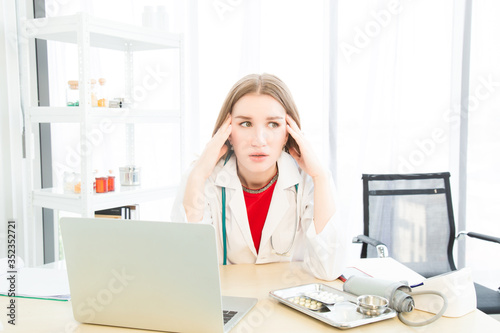 Female beautiful wearing a doctor uniform doing a headache or stressed posture case of treatment. © MikeBiTa