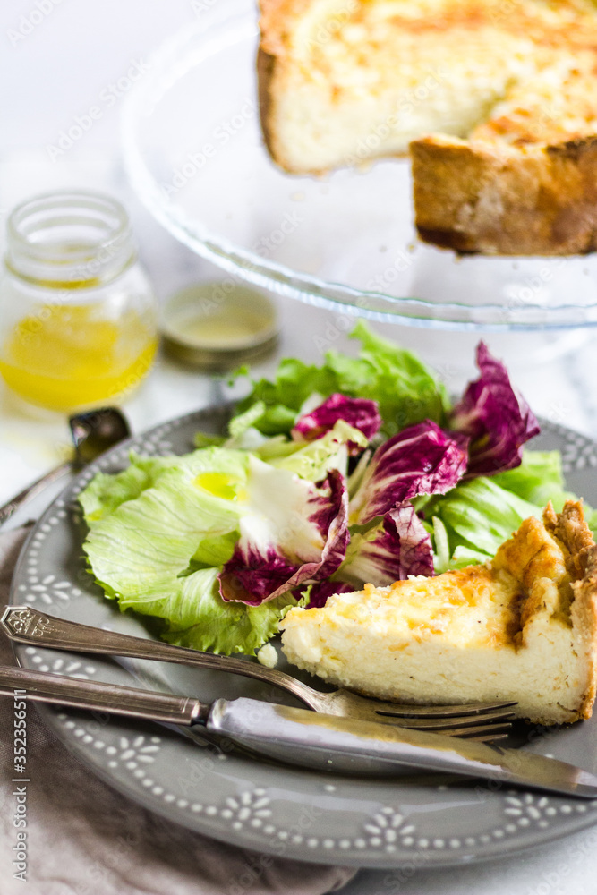 Quiche with colorful salad and dressing on a marble surface Quiche with colorful salad and dressing on a marble surface