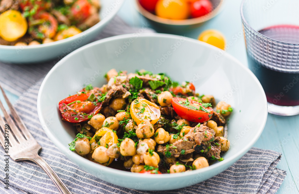 Homemade salad with chickpea, roast beef and cherry tomatoes with red wine on a acqua surface daylight Homemade salad with chickpea, roast beef and cherry tomatoes with red wine on a acqua surface daylight