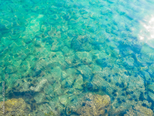 Stone texture under wave blue sea with over light on top view for assembling an article about travel in summer holiday or ocean coast nature.