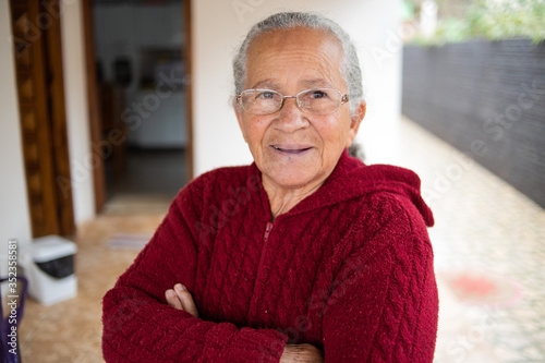 Retrato da mulher idosa de sorriso bonita com cabelo branco e braços cruzados e expressão alegre.