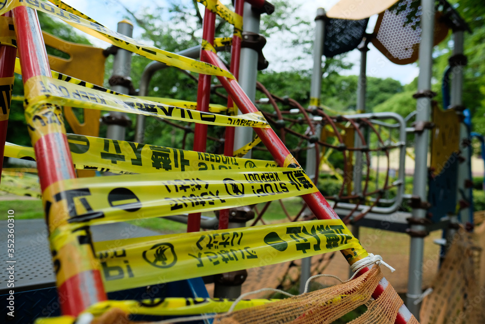 コロナ対策、立ち入り禁止の公園。A playground is caution taped off and closed due to COVID-19. Warning words written in Japanese, Korean, and English.