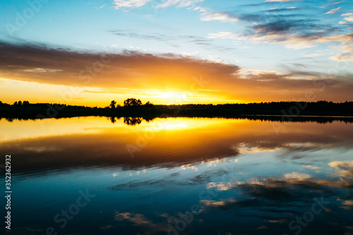 Fototapeta Naklejka Na Ścianę i Meble -  Summer sunset on the lake with a mirror reflection of the sky