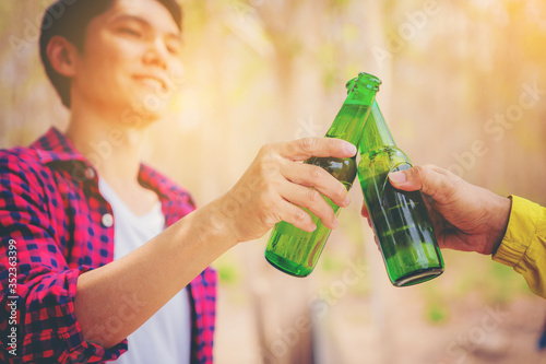 Friends clinking green glass bottles of beer with friendship moment