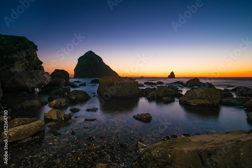 Pacific ocean at sunset, stones and rocks. Landscape, beautiful sunset sky