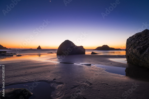 Night beach of the sea or ocean at sunset. Rocks in the water. Night beautiful sky.