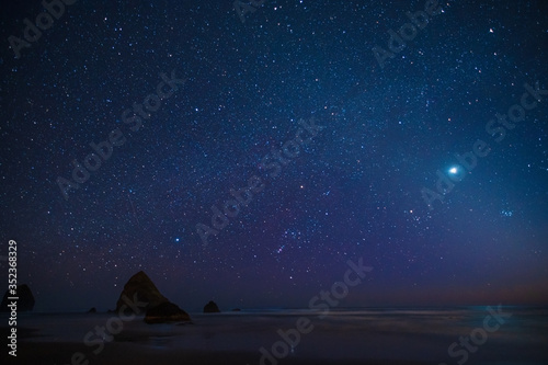 Night beach of the sea or ocean at sunset. Rocks in the water. Night night sky.