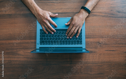 Men's hands in an electronic watch on a laptop keyboard