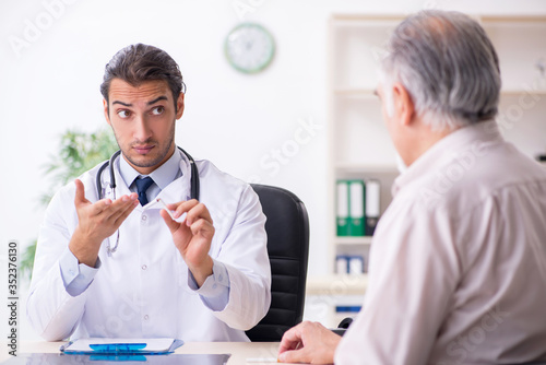 фотографія Young male doctor and old patient in antismoking concept