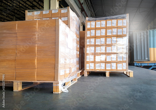 Large shipment pallet goods at interior warehouse dock. Package boxes on pallets. truck docking load cargo at warehouse. Road freight delivery logistics shipping and transport.