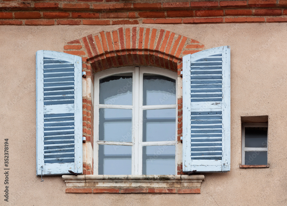 Window with shutters on the wall of the old house