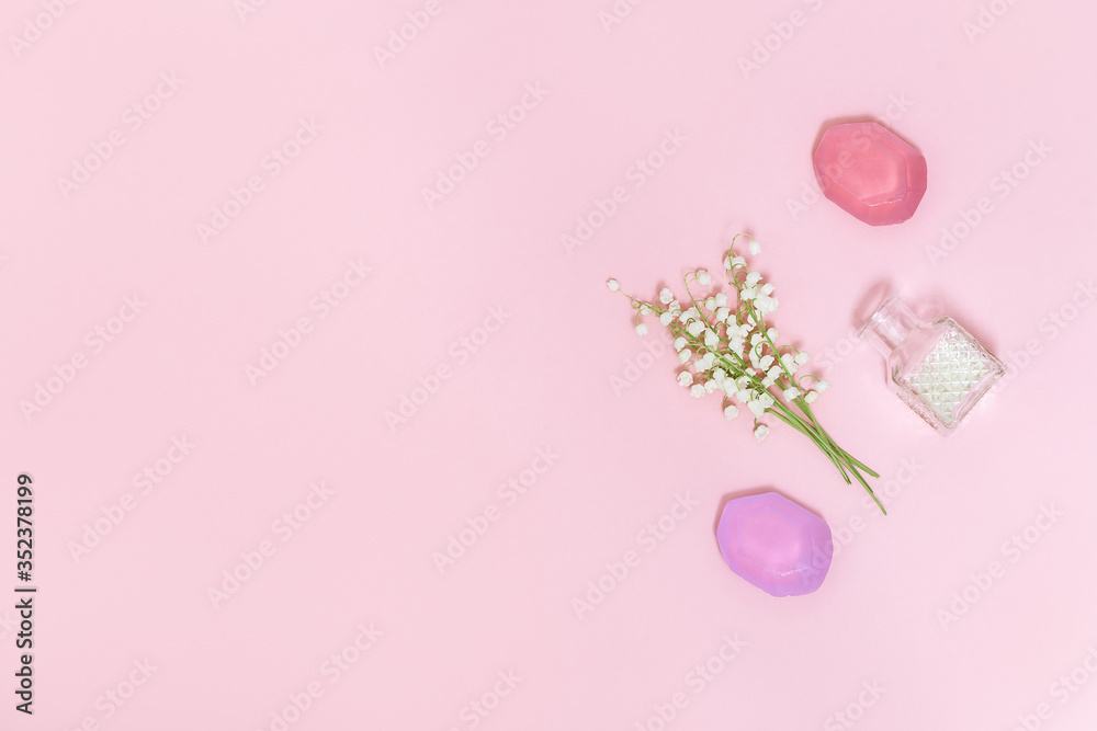 Flowers of lilies of the valley and fragrant soap on soft pink background with free space for text. Handmade soap bars. Aromatherapy, beauty spa background. Top view.