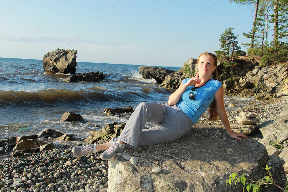 girl sitting on a stone on the shore