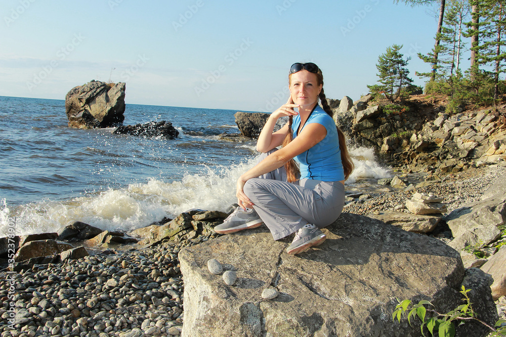 girl sitting on a stone on the shore