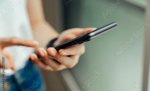 Closeup of young woman hand holding smartphone and chatting with friends at social network.