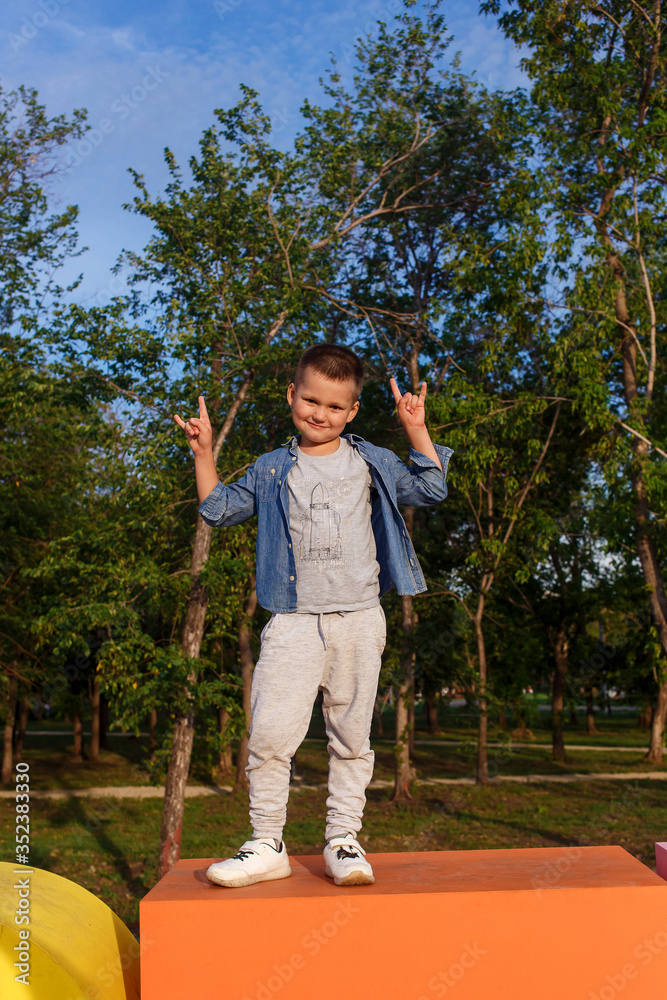 Cute six-year-old smiling boy in gray clothes and denim shirt