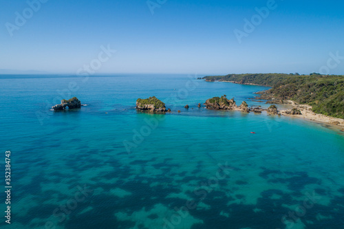 Scenic rock formations in shallow turquoise ocean waters - aerial view with copy space © Greg Brave