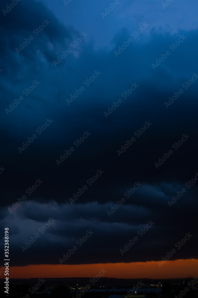 Obraz premium Black thunderclouds at sunset. Bright orange sunset and dark clouds. Storm sky