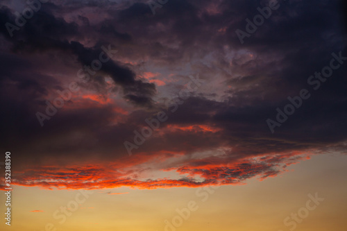 Black thunderclouds at sunset. Bright orange sunset and dark clouds. Storm sky © Kate