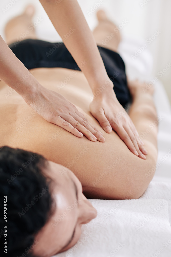 Close-up image of masseuse using fanning technique when massaging back of client Close-up image of masseuse using fanning technique when massaging back of client