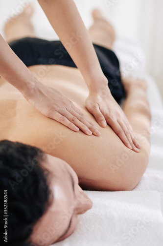 Close-up image of masseuse using fanning technique when massaging back of client