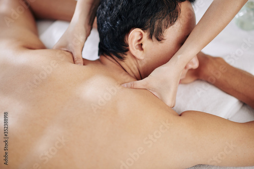 Close-up image of young woman massaging neck and shoulders of client