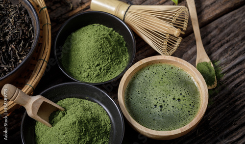 Japanese organic matcha green tea powder in bowl with wire whisk and green tea leaf on wooden background, Organic product from the nature for healthy with traditional style