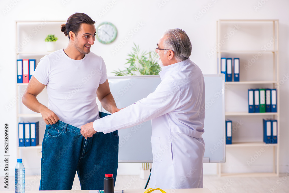 Fototapeta premium Doctor dietician and happy patient wearing large trousers