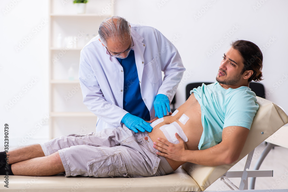 Fototapeta premium Injured young man visiting experienced male doctor