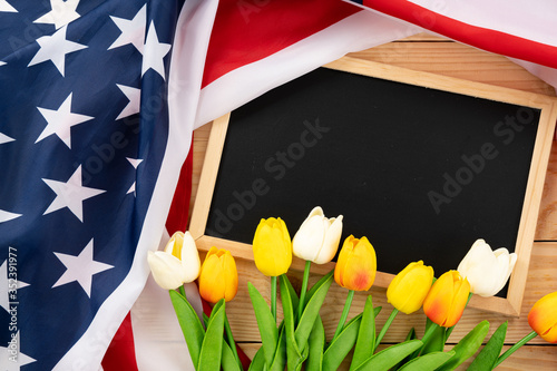 Fototapeta Naklejka Na Ścianę i Meble -  US American flag with blackboard and tulip on wooden background. For USA Memorial day, Presidents day, Veterans day, Labor day, Independence or 4th of July celebration. Top view, copy space for text.