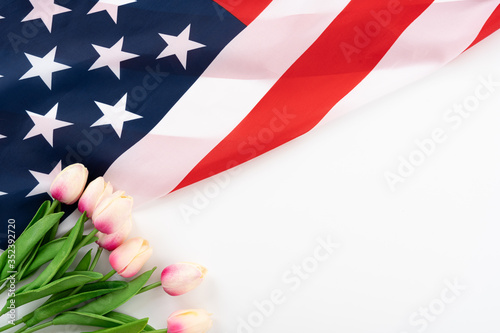 Fototapeta Naklejka Na Ścianę i Meble -  US American flag with tulip flower on white background. For USA Memorial day, Presidents day, Veterans day, Labor day, Independence or 4th of July celebration. Top view, copy space for text.