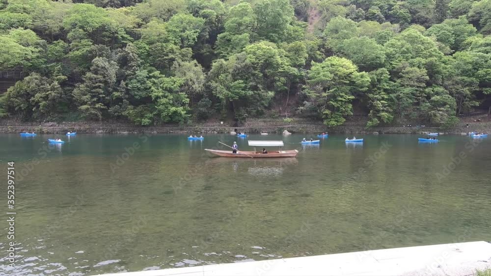 People riding on a boat in Arashiyama River People riding on a boat in Arashiyama River