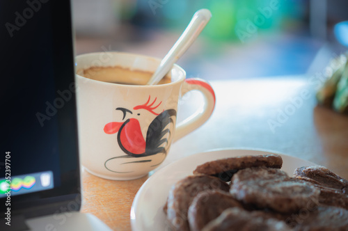 Close-up of coffee cup placed and laptop on the table