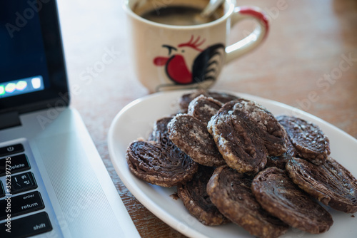 Close-up of Chocolate chip cookies, coffee, laptop on the table.