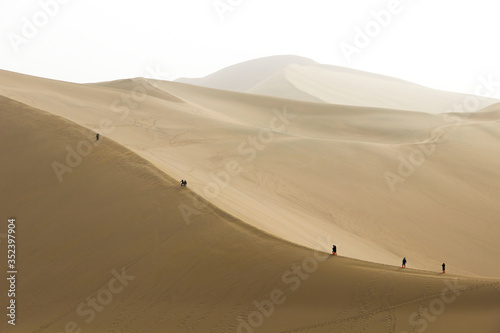Tourists climbing the sand mountain or the singing sand dunes at Mingsha Shan desert as part of the Silk Road  Dunhuang  Gansu  China.