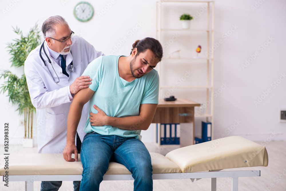 Fototapeta premium Injured young man visiting old doctor