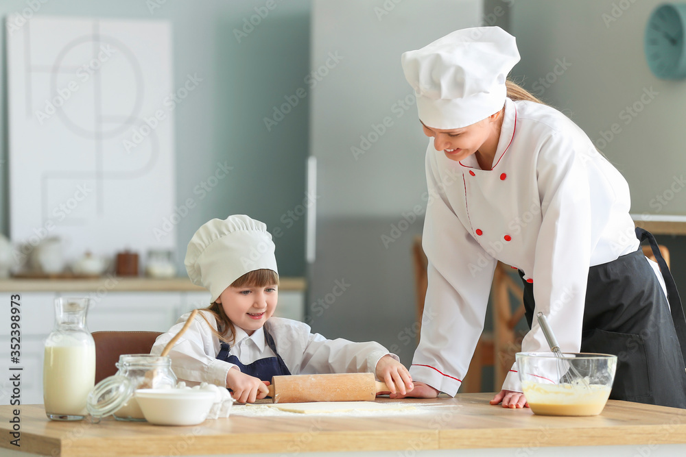 Female chef and her little daughter cooking in kitchen Female chef and her little daughter cooking in kitchen