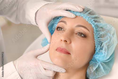 Plastic surgeon examining w...