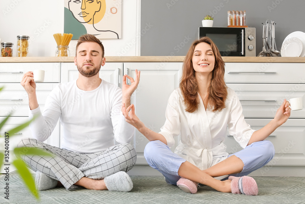 Happy young couple meditating in kitchen