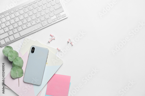 Computer keyboard with notebooks and mobile phone on white background