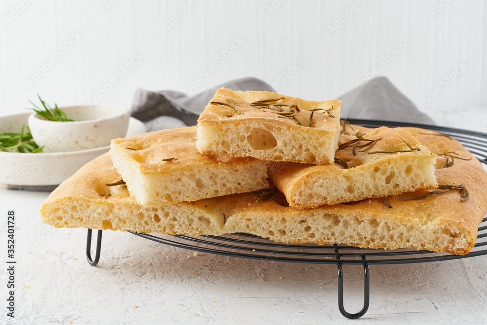 Focaccia, pizza, italian flat bread with rosemary and olive oil on grid