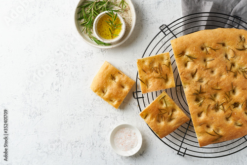 Fotografie Focaccia, pizza, italian flat bread with rosemary and olive oil on grid