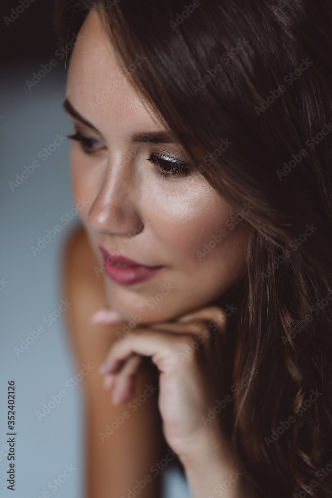 A close-up portrait of a brown-eyed brunette woman of 32 years with beautiful healthy hair in a black top on a white background. Soft selective focus. A close-up portrait of a brown-eyed brunette woman of 32 years with beautiful healthy hair in a black top on a white background. Soft selective focus.