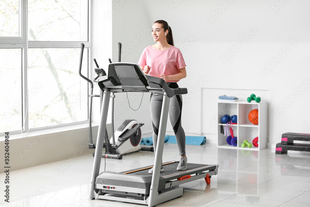 Sporty young woman training on treadmill in gym Sporty young woman training on treadmill in gym