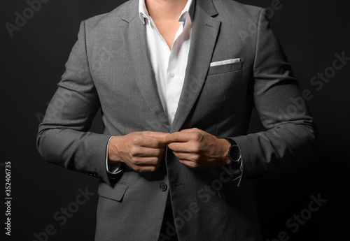 Handsome young man in elegant suit on dark background