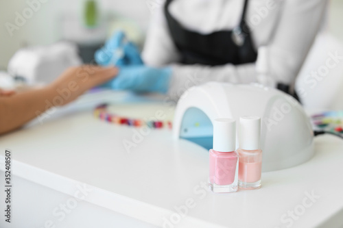 Bottles with cosmetics and lamp for drying gel nail polish in beauty salon